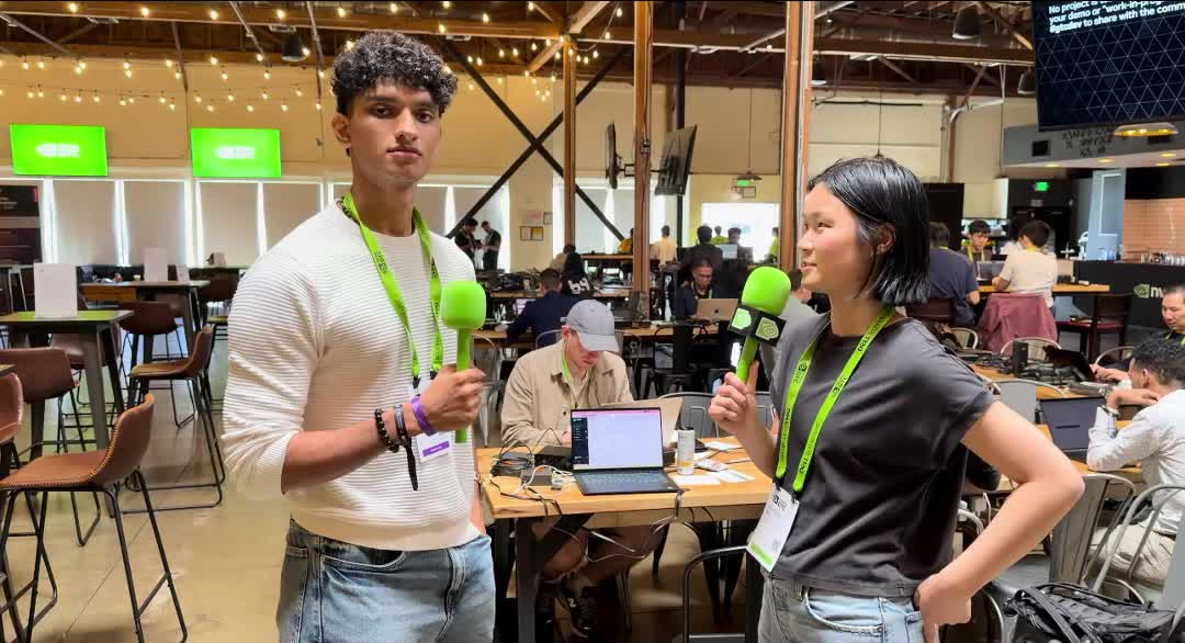 Deon holding a green NVIDIA microphone, interviewing a builder on the NVIDIA hackathon floor